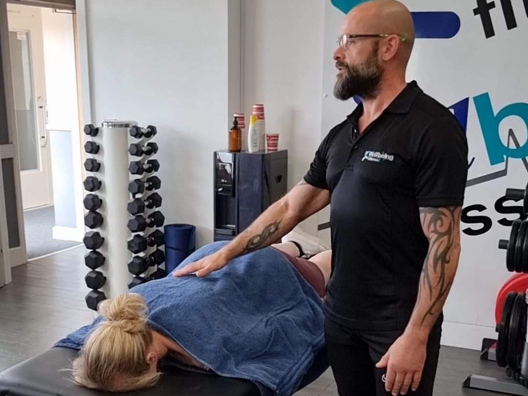 Sports massage tutor demonstrating hands-on techniques on a client at Wellbeing Fitness, Towcester